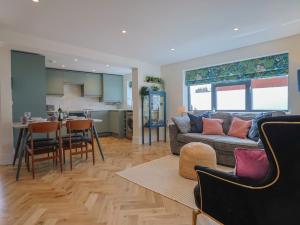 Una sala de estar y una cocina con un sofá y una mesa. en 1 Mill Green Court, en Lyme Regis