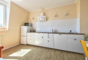 a kitchen with white cabinets and a refrigerator at Monte Cassino 49 by NorthSide Apartments in Sopot