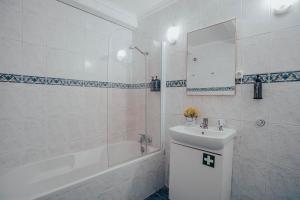 ein weißes Badezimmer mit einem Waschbecken, einer Badewanne und einem Spiegel in der Unterkunft Yellow House - Casa 1 in Angra do Heroísmo + 12 Fotos