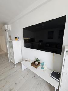 ein weißes Wohnzimmer mit einem großen Flachbildfernseher an der Wand in der Unterkunft Dinas KOKA Resort in Playa del Ingles