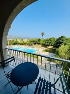 un balcone con tavolo, sedie e piscina di Saint-Florent studio vue piscine a Saint-Florent