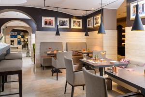 a restaurant with tables and chairs and portraits on the wall at Hotel Indigo Rome - St. George by IHG in Rome