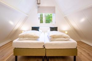 2 bedden in een zolderslaapkamer met een raam bij Boshuisje Rekem - Kitoko in Lanaken