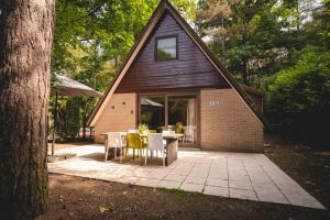 een terras met een tafel en stoelen voor een huis bij Boshuisje Rekem - Kitoko in Lanaken