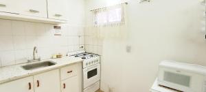 una cucina con piano cottura, lavello e forno a microonde di Complejo Cabañas Las Violetas en Villa Serrana La Gruta a San Andres de las Sierras