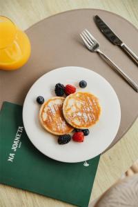 a plate with pancakes and berries on a table at Cala San Miguel Ibiza Resort, Adults only, Curio Collection by Hilton in Puerto de San Miguel