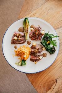 a plate of food with meat and vegetables on a table at Cala San Miguel Ibiza Resort, Adults only, Curio Collection by Hilton in Puerto de San Miguel