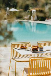 a table with two plates of food on it next to a pool at Cala San Miguel Ibiza Resort, Adults only, Curio Collection by Hilton in Puerto de San Miguel