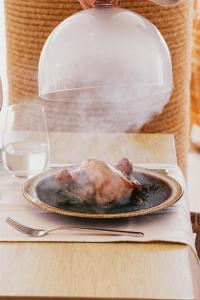 a chicken on a plate on a table with a glass of water at Cala San Miguel Ibiza Resort, Adults only, Curio Collection by Hilton in Puerto de San Miguel