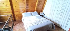 una camera da letto con un letto in una stanza di legno di Complejo Cabañas Las Violetas en Villa Serrana La Gruta a San Andres de las Sierras