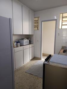 a kitchen with white cabinets and a sink and a door at Mônaco 301 in Niterói