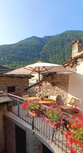 balkon ze stolikami z kwiatami i parasolem w obiekcie Medieval Hamlet Malpertus w mieście Bobbio Pellice