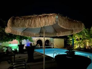 a large straw umbrella next to a swimming pool at night at Bordeaux Castle natural No2 in Quinsac +10 photos