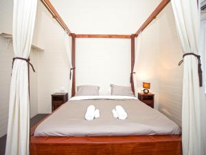 1 dormitorio con cama con dosel y zapatillas blancas en CBD Holiday Home, en Mackay
