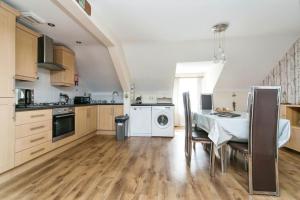 a kitchen with a table and a dining room at The Penthouse at Beach Court in Trearddur
