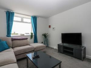 a living room with a couch and a flat screen tv at Cwtch y Môr in Holyhead