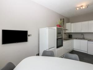 a kitchen with white cabinets and a white refrigerator at Cwtch y Môr in Holyhead