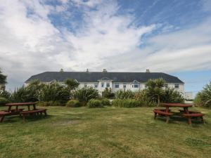 two picnic tables in front of a white house at Cwtch y Môr in Holyhead