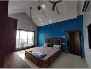 a bedroom with a bed with blue walls and a window at Luxury villa in Mumbai