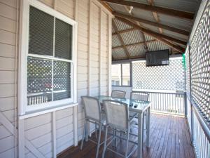 a screened porch with a table and chairs and a television at CBD Holiday Home in Mackay