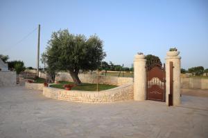 a stone fence with a gate and a tree at Dimora Sasa in Putignano