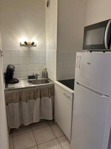 ニームにあるstudio Nimes capouchiné parking et balcon proche centreのシンクと白い冷蔵庫のあるキッチン +17枚の写真