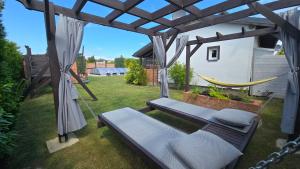 a hammock in a backyard with a pergola at Domek parterowy apartamentowy Ostoja in Rewal