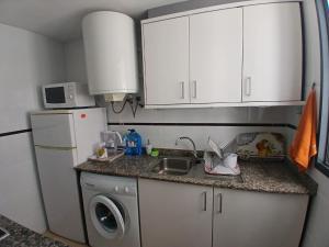 a small kitchen with a sink and a refrigerator at Tikitita House in Gandía