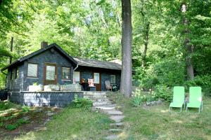 皮尔纳Waldsaumhütte mit Ausblick的前面有两把绿色椅子的小房子