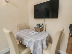 une table avec des chaises et une télévision murale dans l'établissement Midsummer Cottage, à Wilton