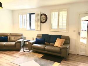 a living room with a couch and a clock on the wall at Shangri - La Spacious Family Townhouse in Killarney
