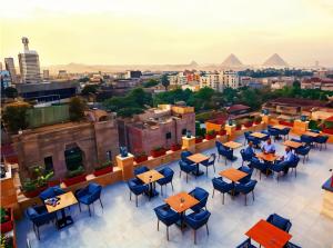 vista sulle piramidi da un ristorante all'ultimo piano con tavoli e sedie di THree PYramiDs & SPhinX HoTeL a Il Cairo