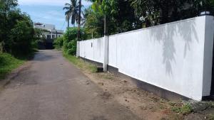 an empty road next to a white wall at Peacock House in Kotugoda