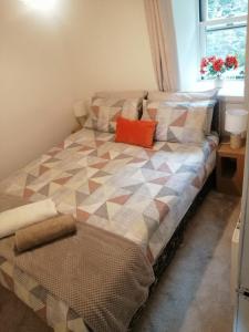 a bed with an orange pillow on it in a room at Castle Walk Apartment in Stirling