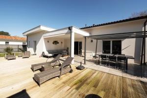 een patio met een tafel en stoelen op een houten terras bij Maison Landes in Mées