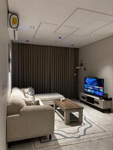 een woonkamer met een bank en een tv bij Comfy apartment in AlKhobar in Al Khobar