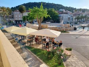 a group of people sitting at tables under umbrellas at Apartment Nona in Korčula