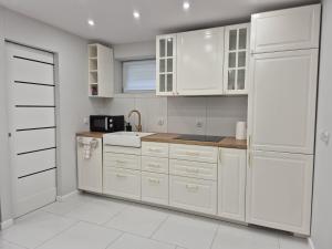 a white kitchen with white cabinets and a sink at NEW STORY Apartment in Sława