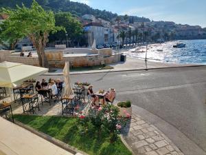 a group of people sitting at tables near the water at Apartment Nona in Korčula
