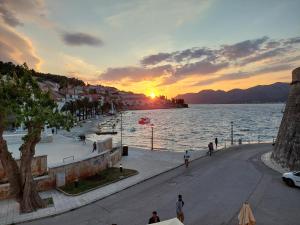 a sunset over the water with people walking on a street at Apartment Nona in Korčula +6 photos