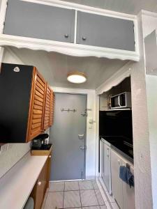 a small kitchen with white cabinets and a door at Modern studio auzet col du fanget, site nordique in Auzet