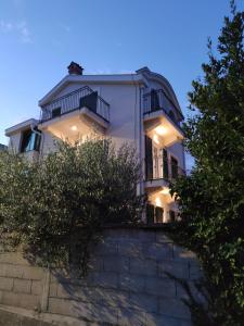 a large white house with balconies on top of a wall at Villa Verde Oliva in Kamenari