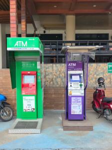 two atm machines sitting next to a motor scooter at Hotel De Khuvieng in Chiang Mai