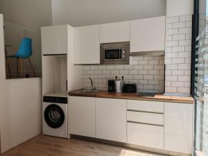 a kitchen with white cabinets and a microwave at Bilbao ROOMS & KITCHEN Rekalde in Bilbao