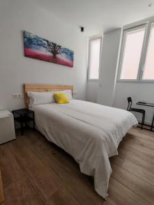 a bedroom with a large white bed with a yellow pillow at Bilbao ROOMS & KITCHEN Rekalde in Bilbao +11 photos