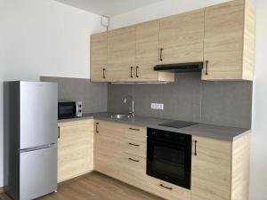 a kitchen with wooden cabinets and a white refrigerator at Juniper 2 Studio in Kecskemét