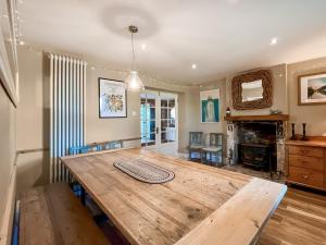 une salle à manger avec une table en bois et une cheminée dans l'établissement Mews Cottage, à Trowbridge