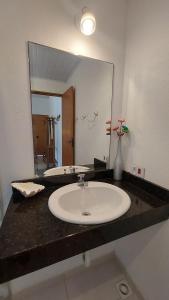 a bathroom with a sink and a large mirror at Suítes Paquetá Ilhabela in Ilhabela