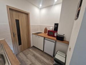 a small kitchen with a door and a microwave at FeWo Herzenstölen in Sebnitz