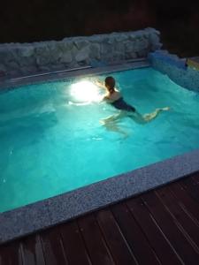 a person swimming in a swimming pool at night at Robinson Horseville in Karlovac
